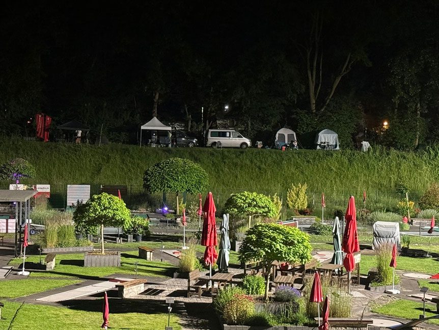 Die Minigolfanlage im Sportpark Eickel bei Nacht, dahinter am Hang Zelte und Campingbusse der Läuferinnen und Läufer